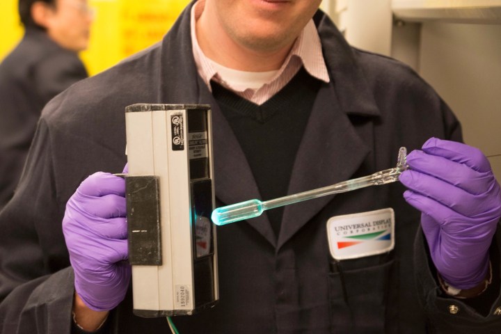 Universal Display Corporation chemist illuminating developmental phosphorescent blue OLED materials in R&D lab.