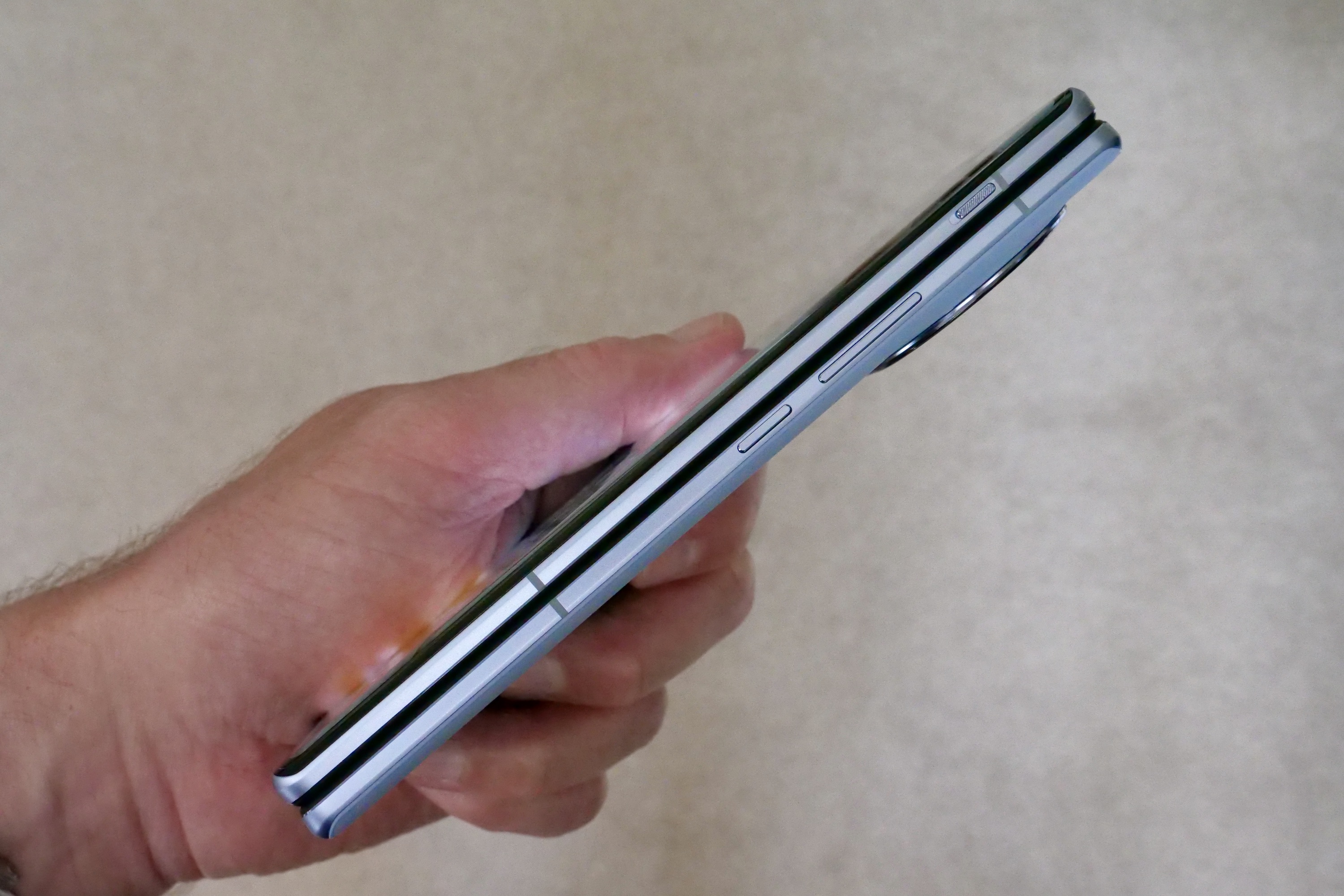A person holding the Vivo X Fold 2 and showing the side of the device.