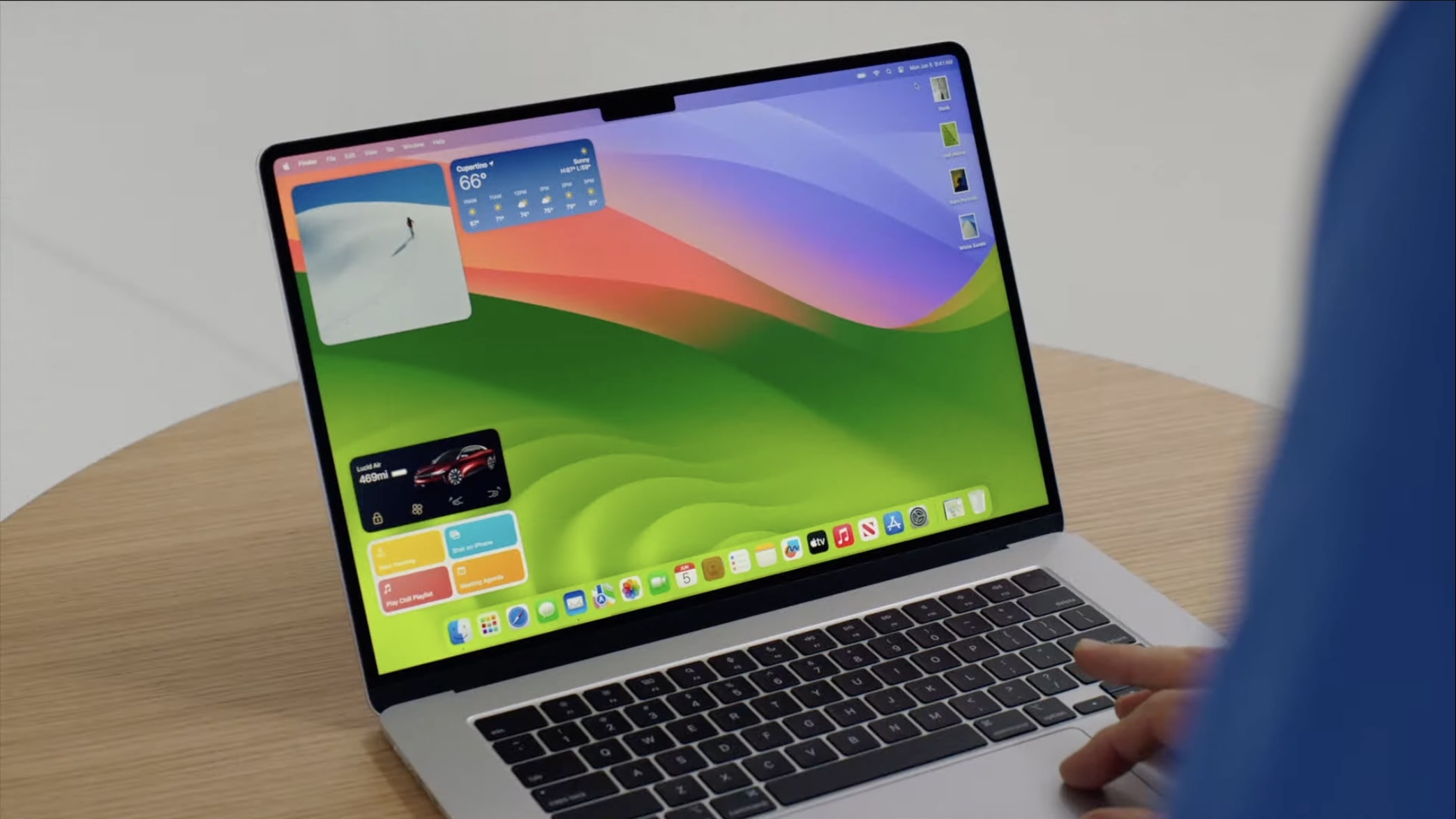 एक डेस्क पर एप्पल का 15-इंच मैकबुक एयर, इसके डिस्प्ले पर मैकओएस सोनोमा चल रहा है।