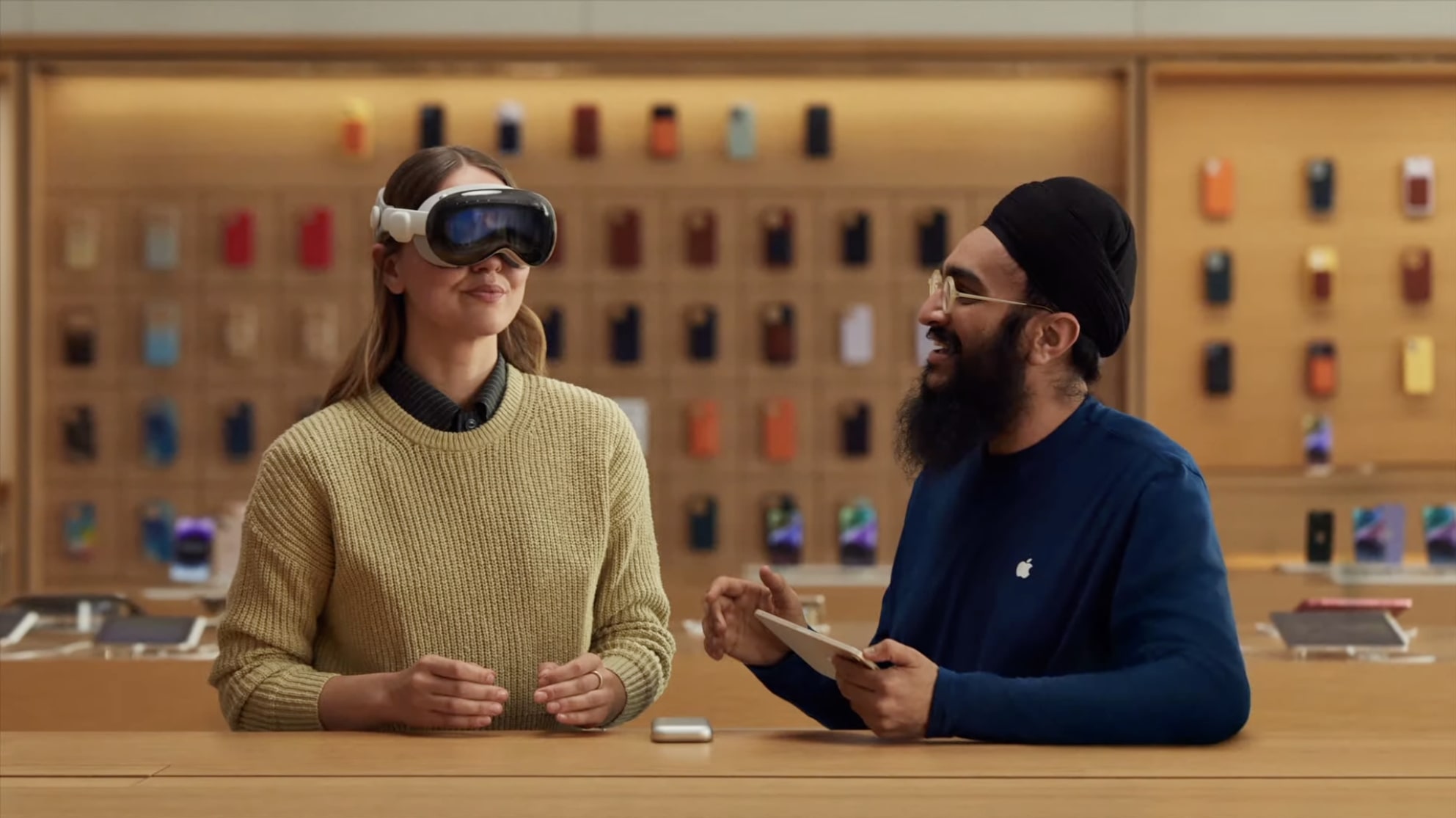 Uma pessoa experimenta um fone de ouvido de realidade mista Apple Vision Pro em uma Apple Store, com um funcionário da Apple ao lado dela.
