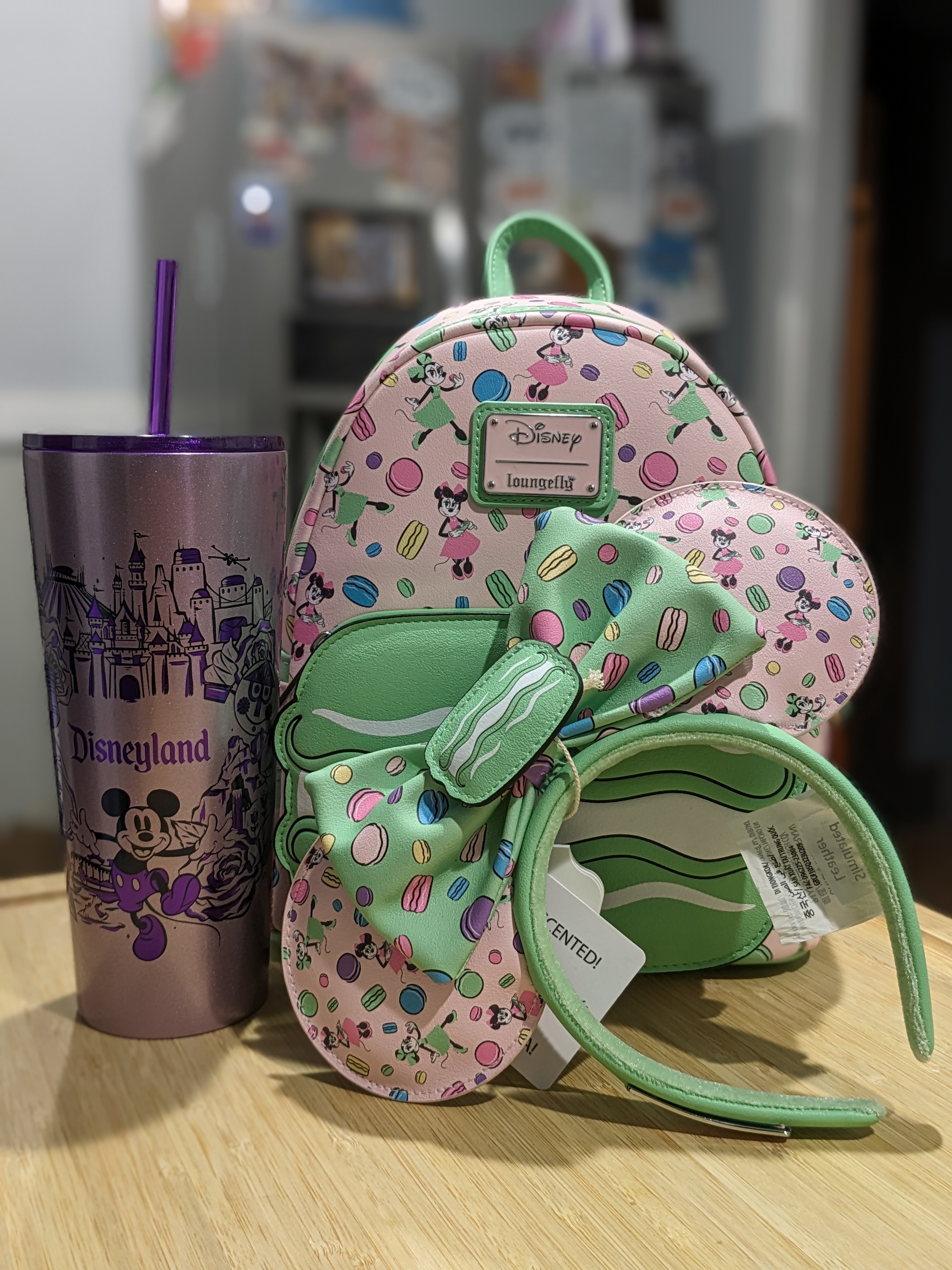 Purple Disneyland Starbucks tumbler and Minnie Mouse Macaron Ears and Loungefly Backpack portrait taken with Google Pixel Fold.