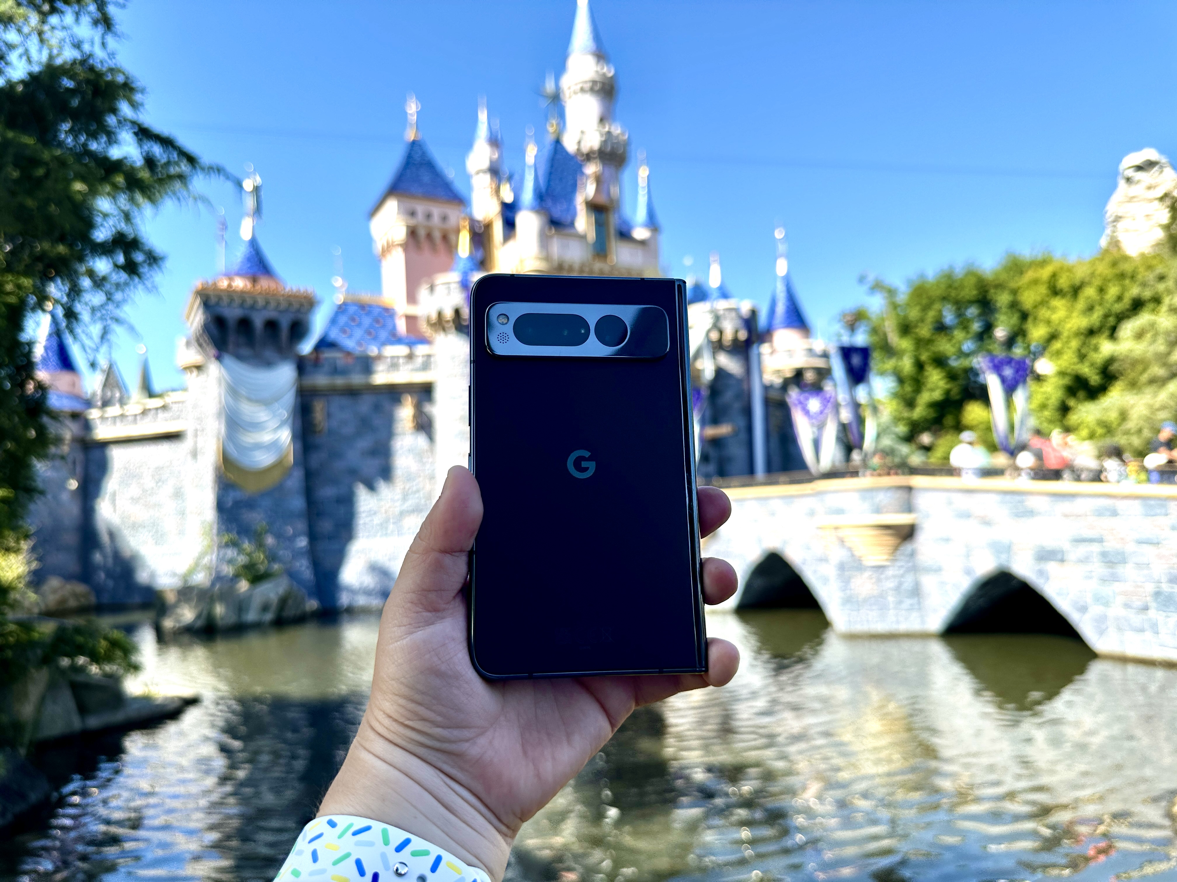 Google Pixel Fold in Obsidian in hand at Disneyland castle.