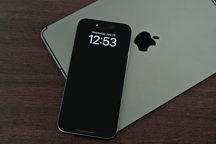 iPhone 14 Pro Max colocado encima del iPad mostrando una pantalla siempre encendida con el fondo de pantalla desactivado.