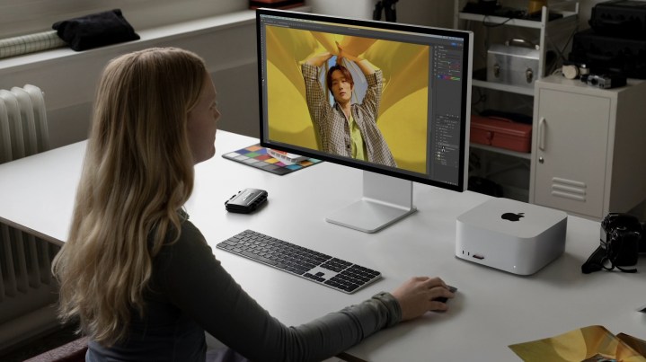 Una mujer se sienta en un escritorio con el M2 Mac Studio en él.
