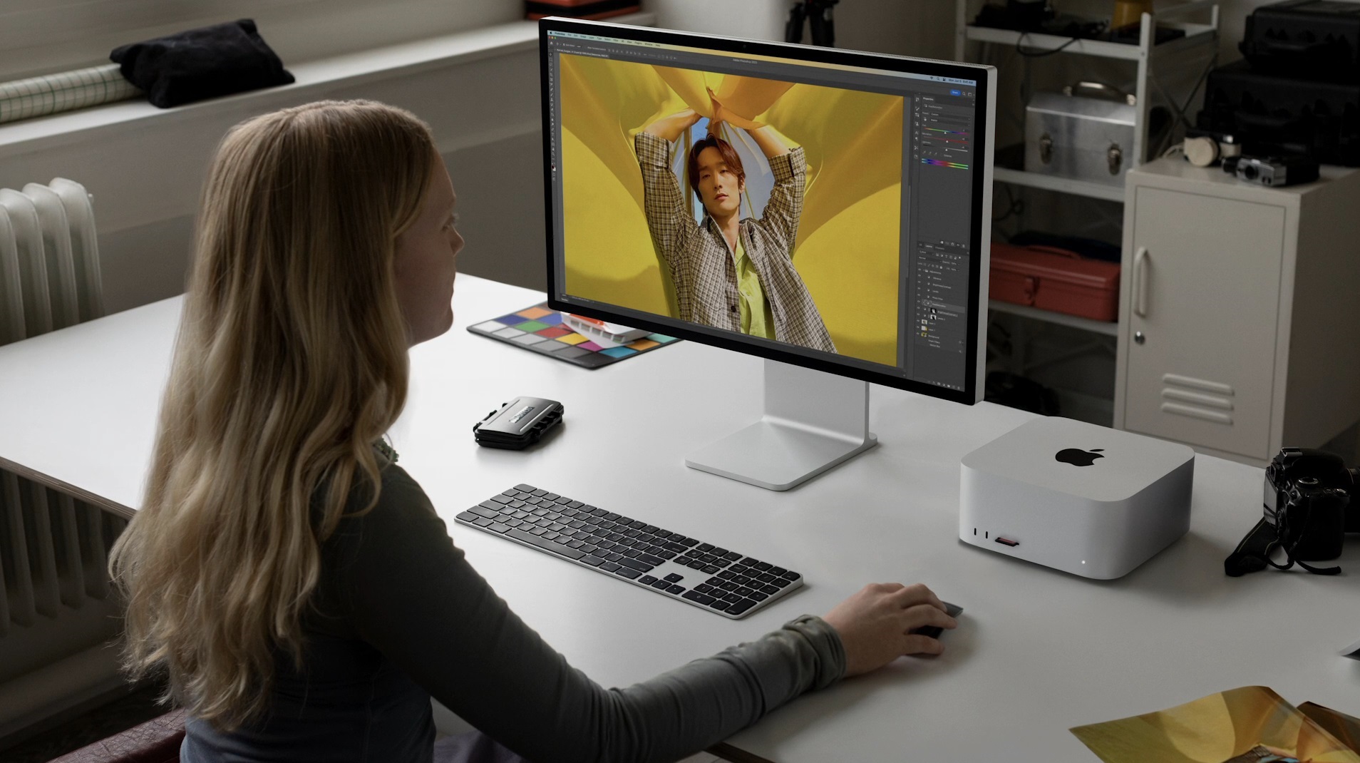 Uma mulher está sentada em uma mesa com o M2 Mac Studio sobre ela.