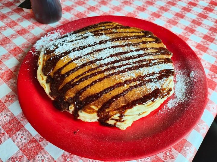 Pancake con gocce di cioccolato su un piatto rosso, scattati con il Motorola Razr Plus.