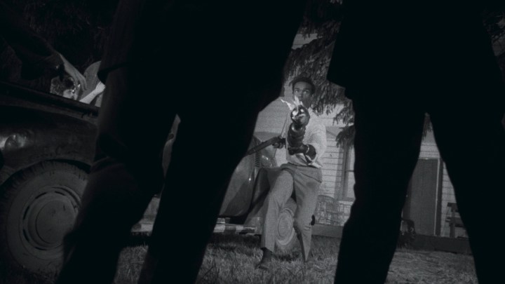A Black Man carries a torch in Night of the Living Dead.