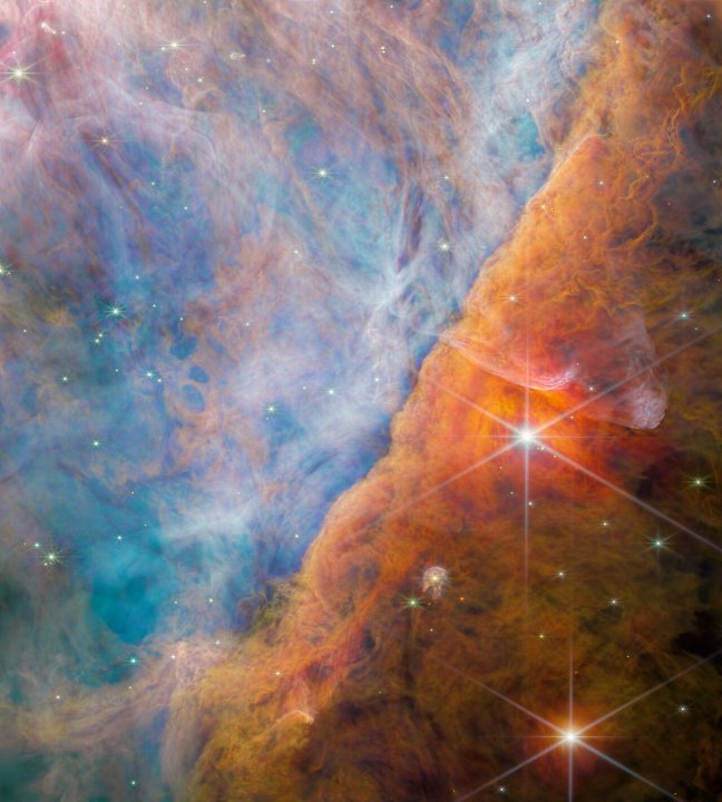 This image is NIRCam’s view of the Orion Bar region studied by the team of astronomers. Bathed in harsh ultraviolet light from the stars of the Trapezium Cluster, it is an area of intense activity, with star formation and active astrochemistry. This made it a perfect place to study the exact impact that ultraviolet radiation has on the molecular makeup of the discs of gas and dust that surround new stars. The radiation erodes the nebula’s gas and dust in a process known as photoevaporation; this creates the rich tapestry of cavities and filaments that fill the view. The radiation also ionises the molecules, causing them to emit light — not only does this create a beautiful vista, it also allows astronomers to study the molecules using the spectrum of their emitted light obtained with Webb’s MIRI and NIRSpec instruments.