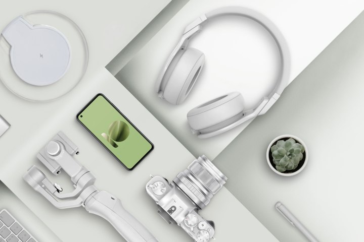 Una imagen del ZenFone 10 acostado sobre una mesa dispuesta junto a algunos accesorios del teléfono como auriculares y cargadores.