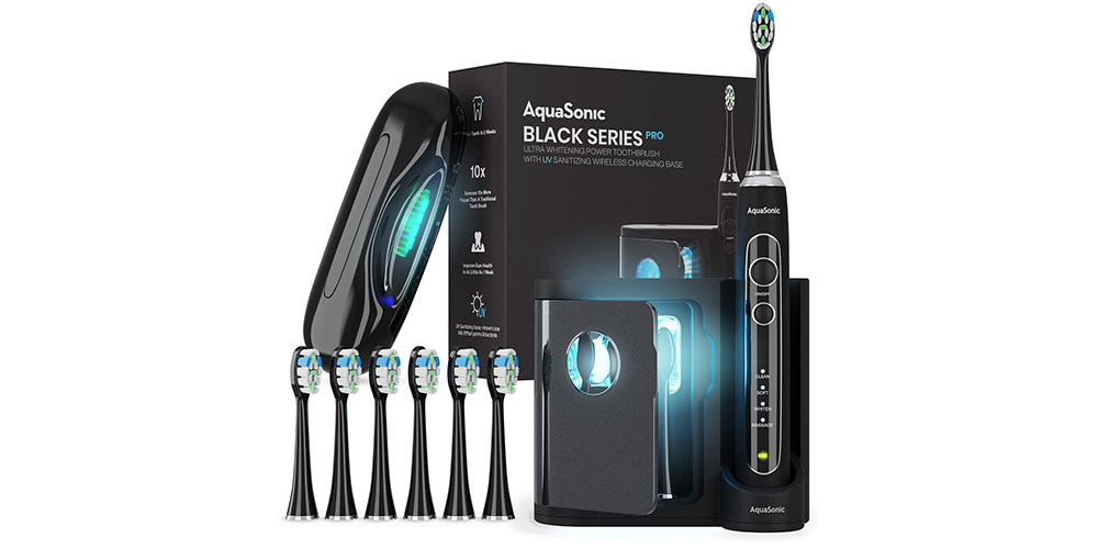 A escova de dentes Aquasonic Black Series Pro em um fundo branco e ao lado de muitas cabeças de escova.