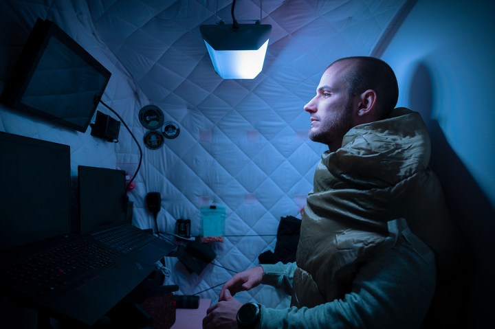 Un hombre trabaja en una pequeña habitación con una luz de ritmo circadiano en un ajuste azul. 