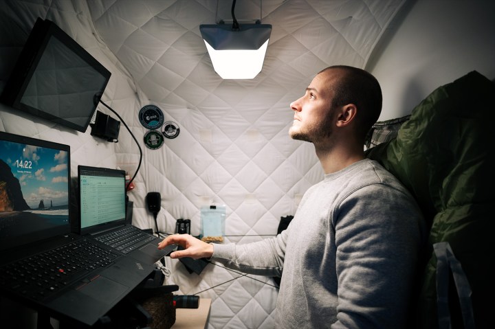 Un hombre trabaja en una pequeña habitación con una luz circadiana a la luz del día. 