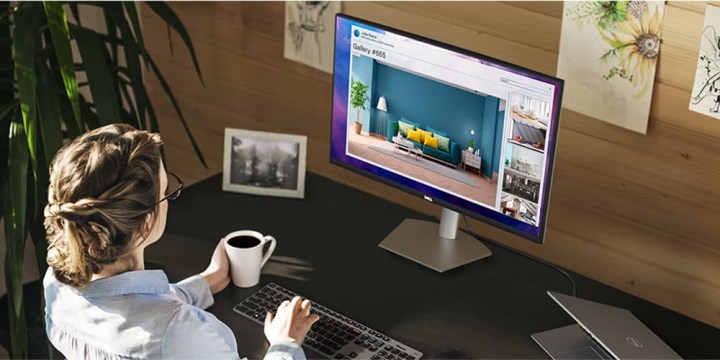 The Dell 27-inch QHD monitor placed on a desk while someone sits nearby using the computer.