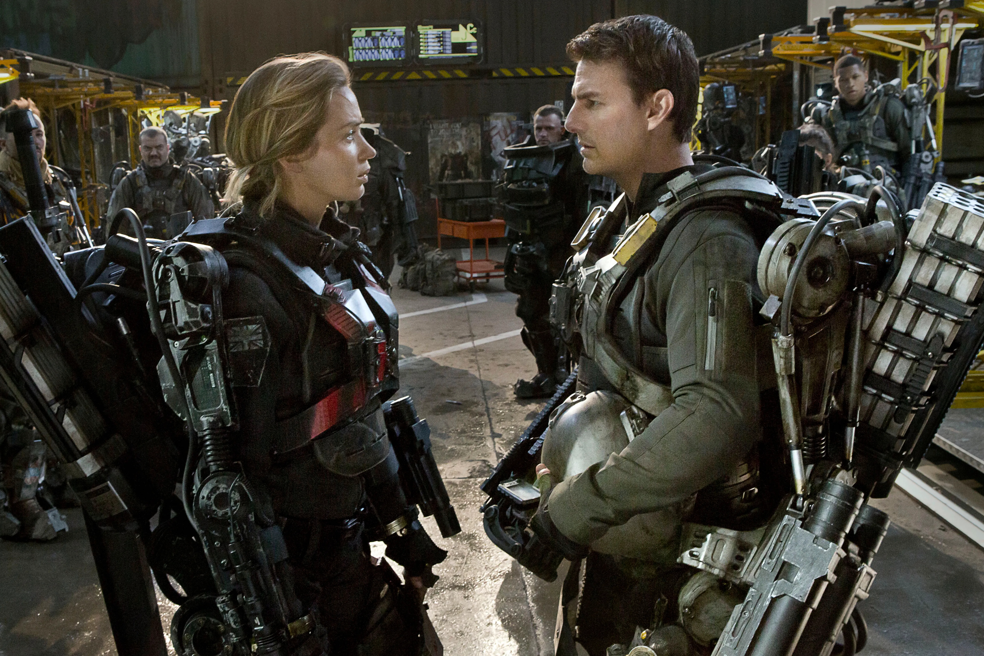 Emily Blunt and Tom Cruise face each other while wearing mech suits in Edge of Tomorrow.