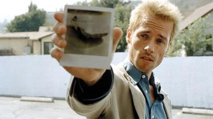 Guy Pearce as Leonard Shelby showing a polaroid to the camera in Memento.
