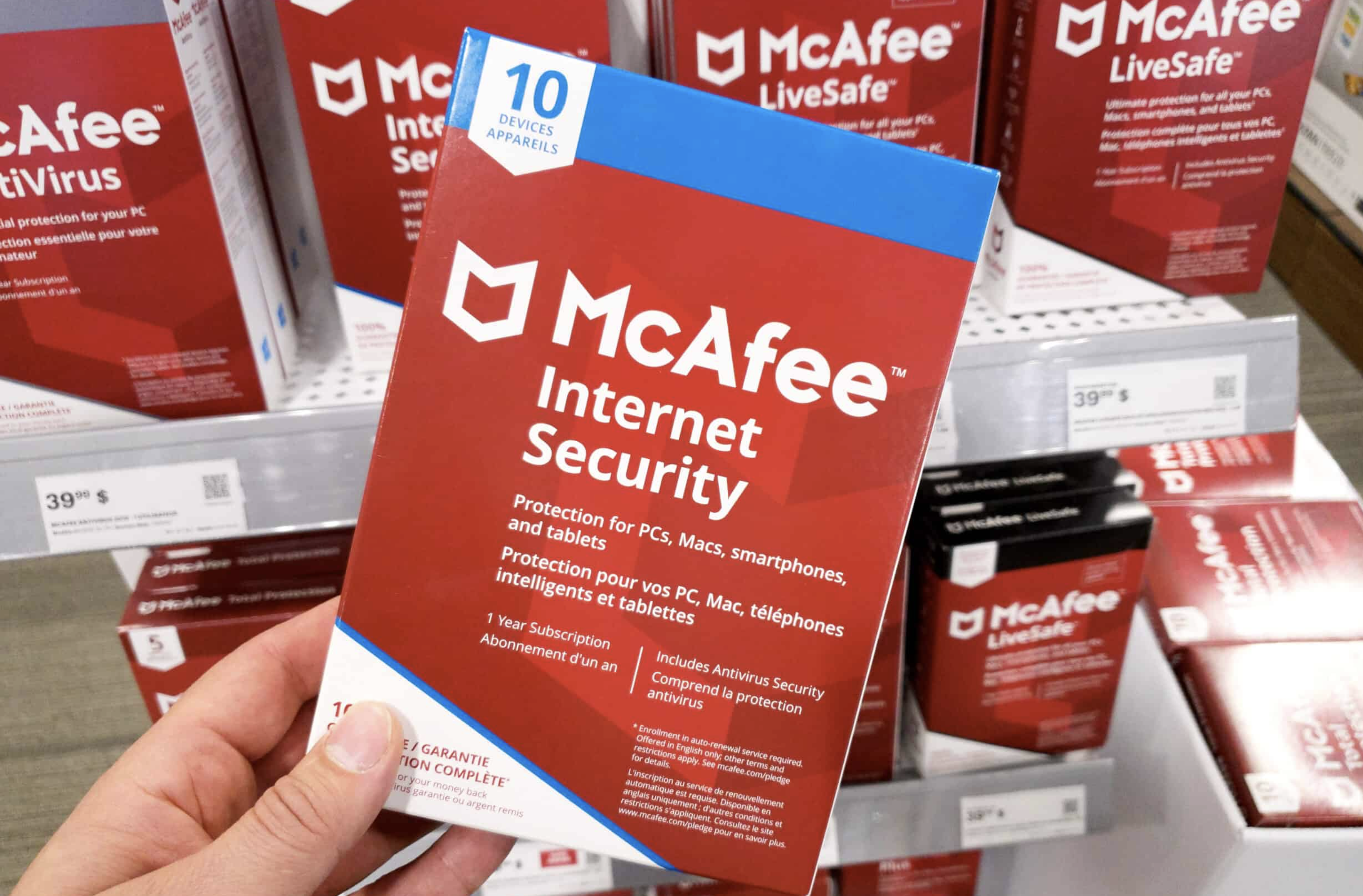 A person holding a phsyical copy of McAfee Antivirus in a retail store.