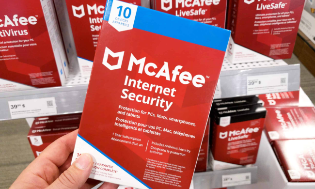 A person holding a phsyical copy of McAfee Antivirus in a retail store.
