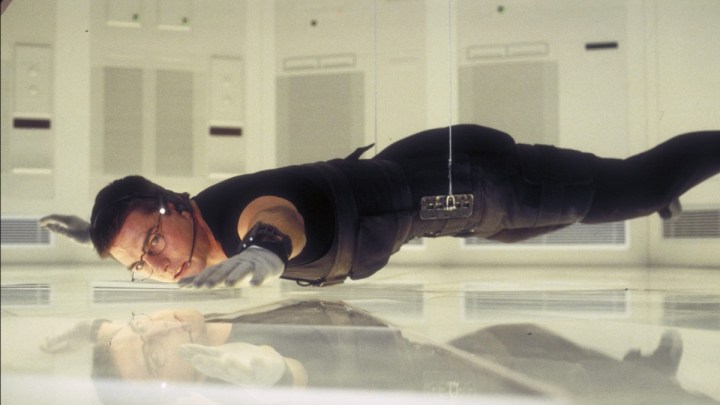 Tom Cruise as Ethan Hunt hanging above the floor in Mission: Impossible.