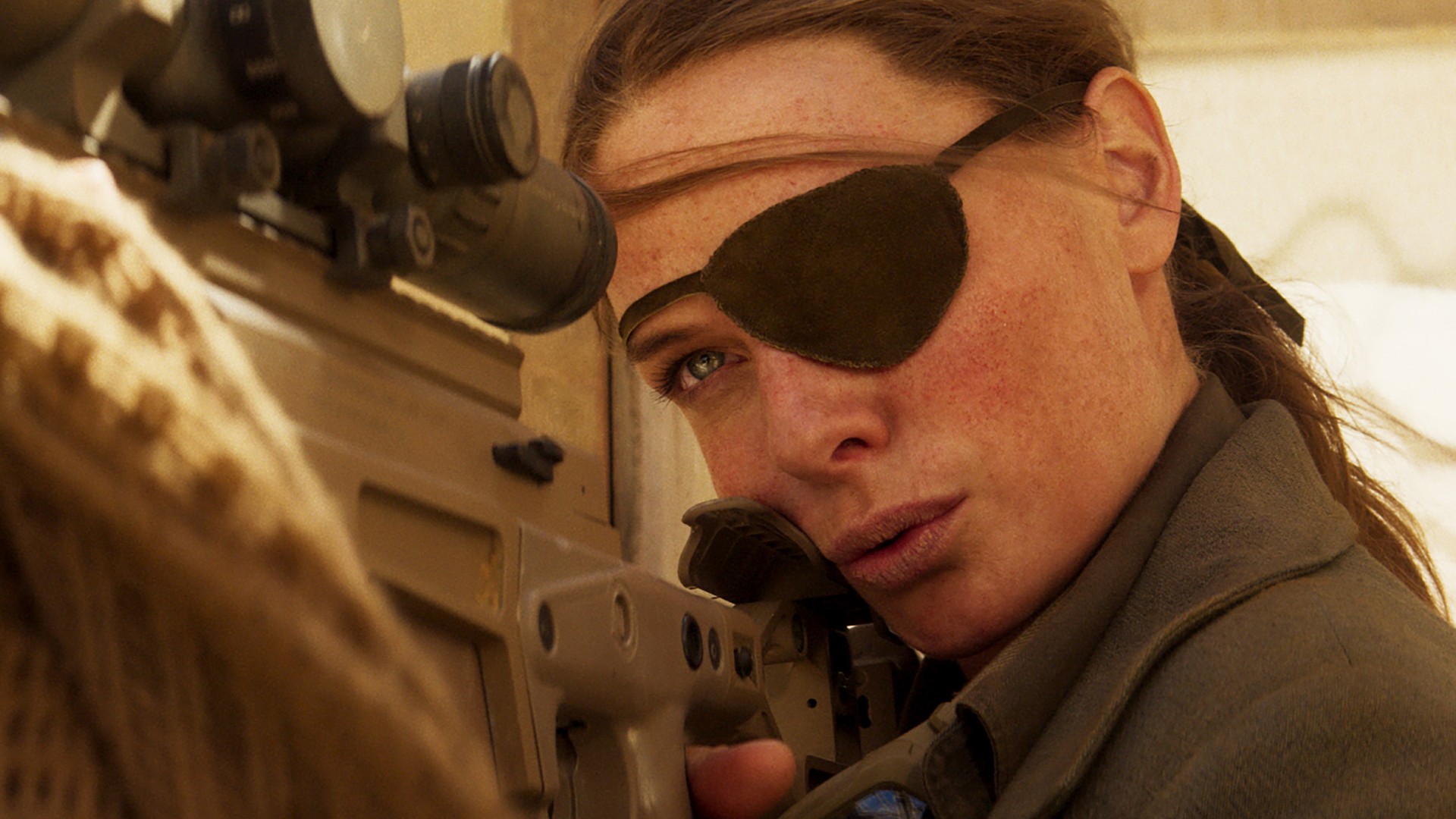 Rebecca Ferguson com um tapa-olho alinha um tiro com seu rifle de precisão.