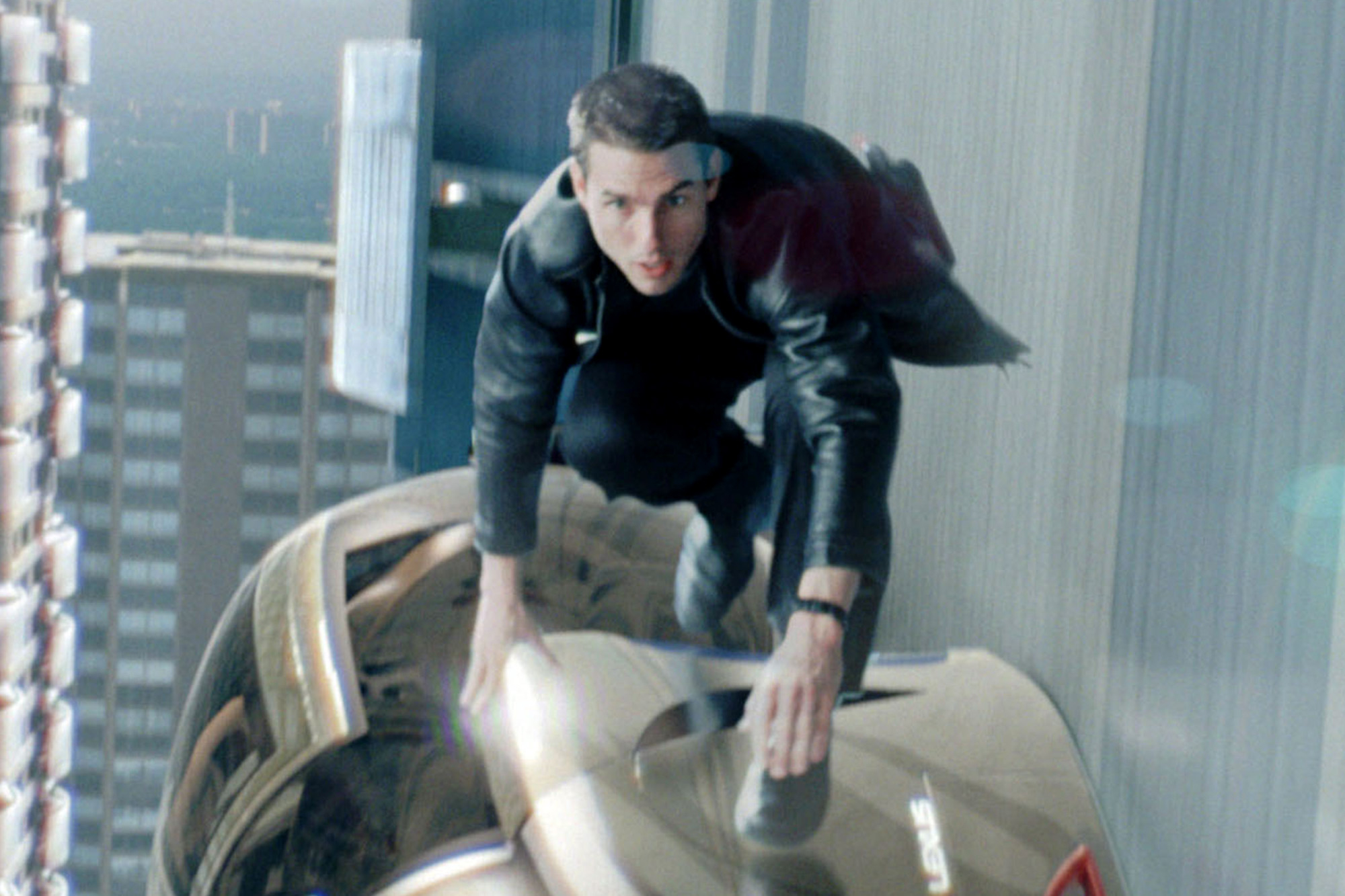 Tom Cruise está em cima de um carro futurista em Minority Report.