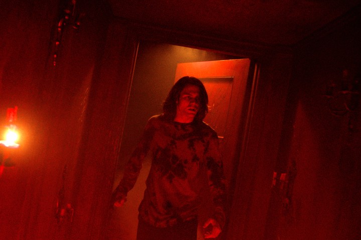 Ty Simpkins está em uma porta vermelha em Insidious: The Red Door.
