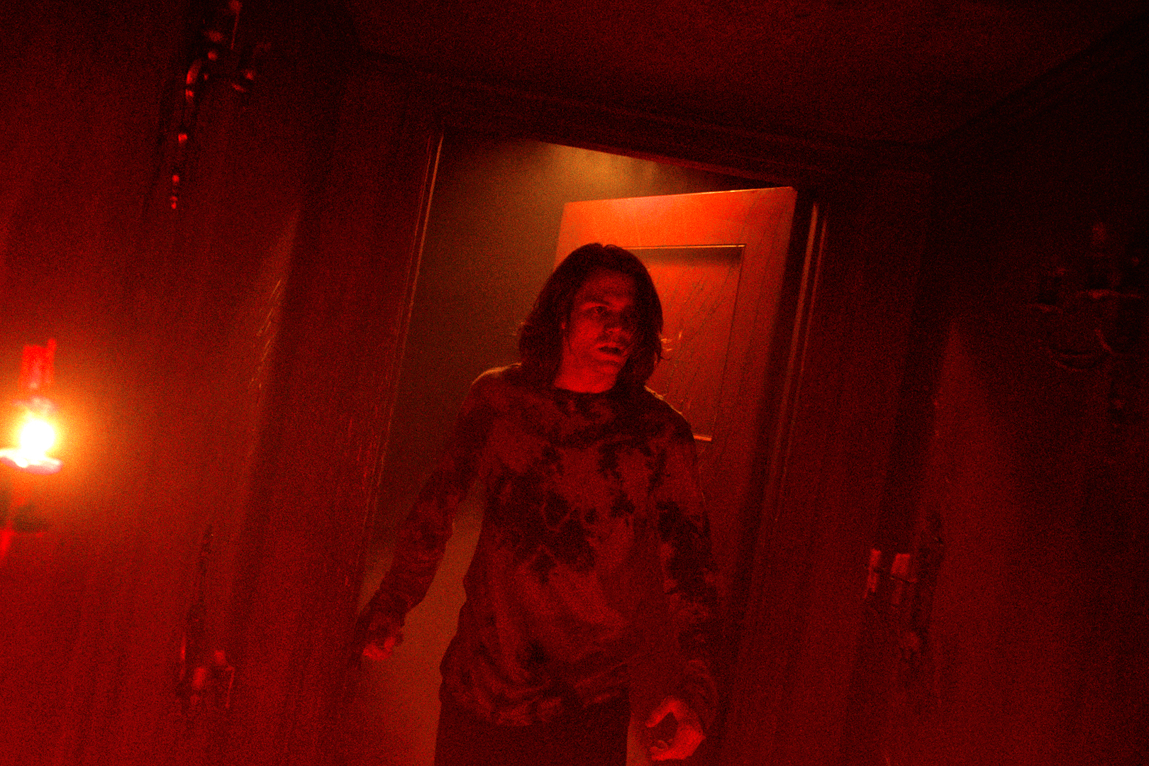 Ty Simpkins stands in a red doorway in Insidious: The Red Door.