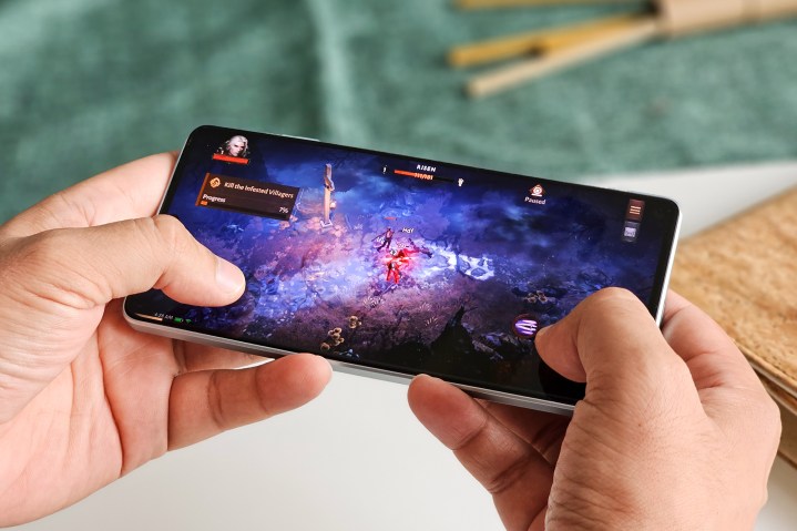 Man playing Diablo Immortal Android game on Xiaomi POCO F5.