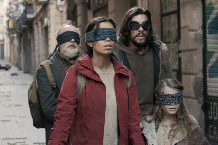 A blindfolded family walks in a street in Bird Box Barcelona.