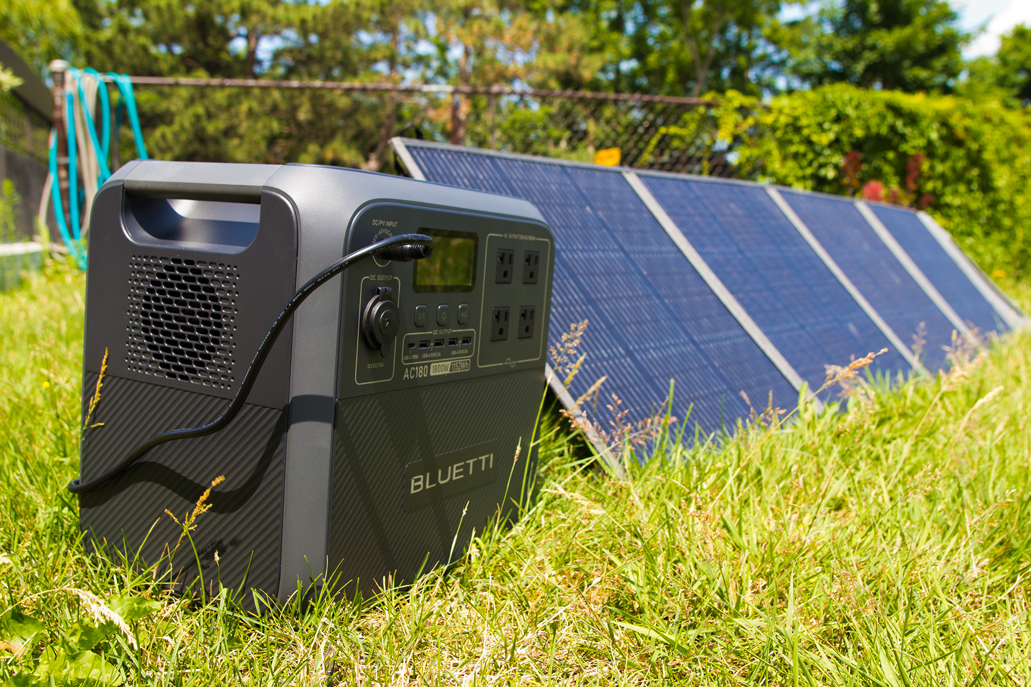 A central elétrica Bluetti AC180 conectada a painéis solares em um gramado. 