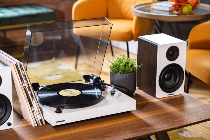 The Fluance RT81+ Elite turntable with a white speaker on a table.