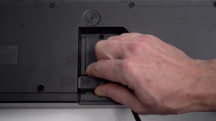 A man's hand inserting a cable into the HDMI ARC port on the back of a TV. 