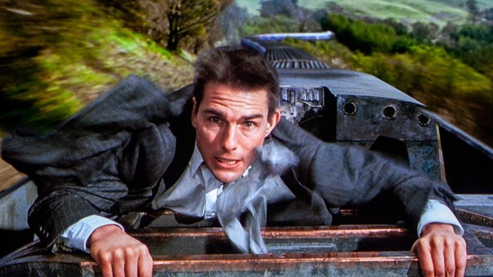 A man climbs on top of a train in Mission: Impossible.