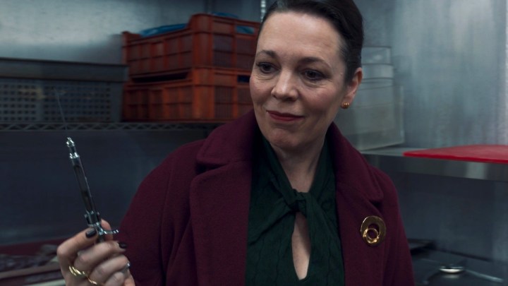 Olivia Colman looking at a knife in a red coat in Secret Invasion.