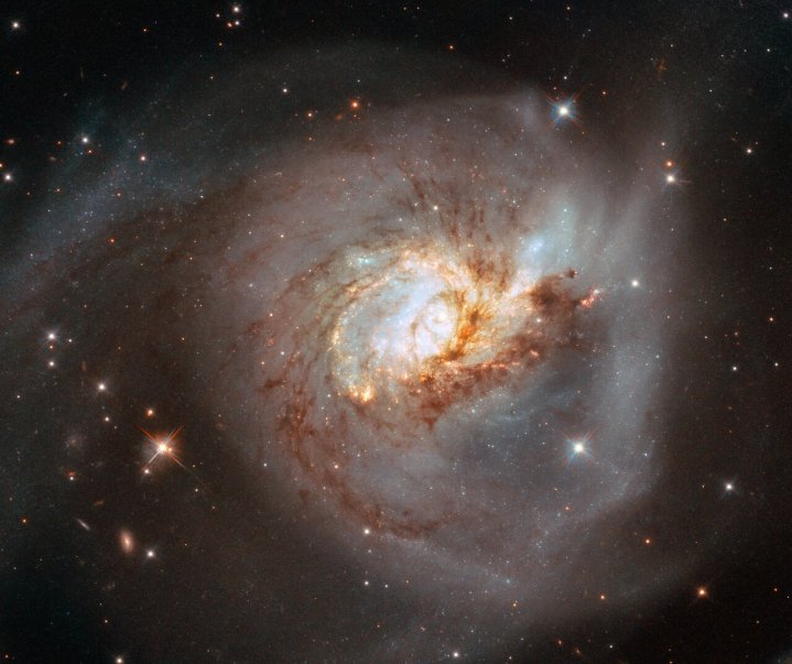 A peculiar galáxia NGC 3256 ocupa o centro do palco nesta imagem do Telescópio Espacial Hubble da NASA/ESA.  Esta galáxia distorcida é o destroço de uma colisão frontal entre duas galáxias espirais que provavelmente ocorreu há 500 milhões de anos, e está repleta de aglomerados de estrelas jovens que se formaram quando o gás e a poeira das duas galáxias colidiram.