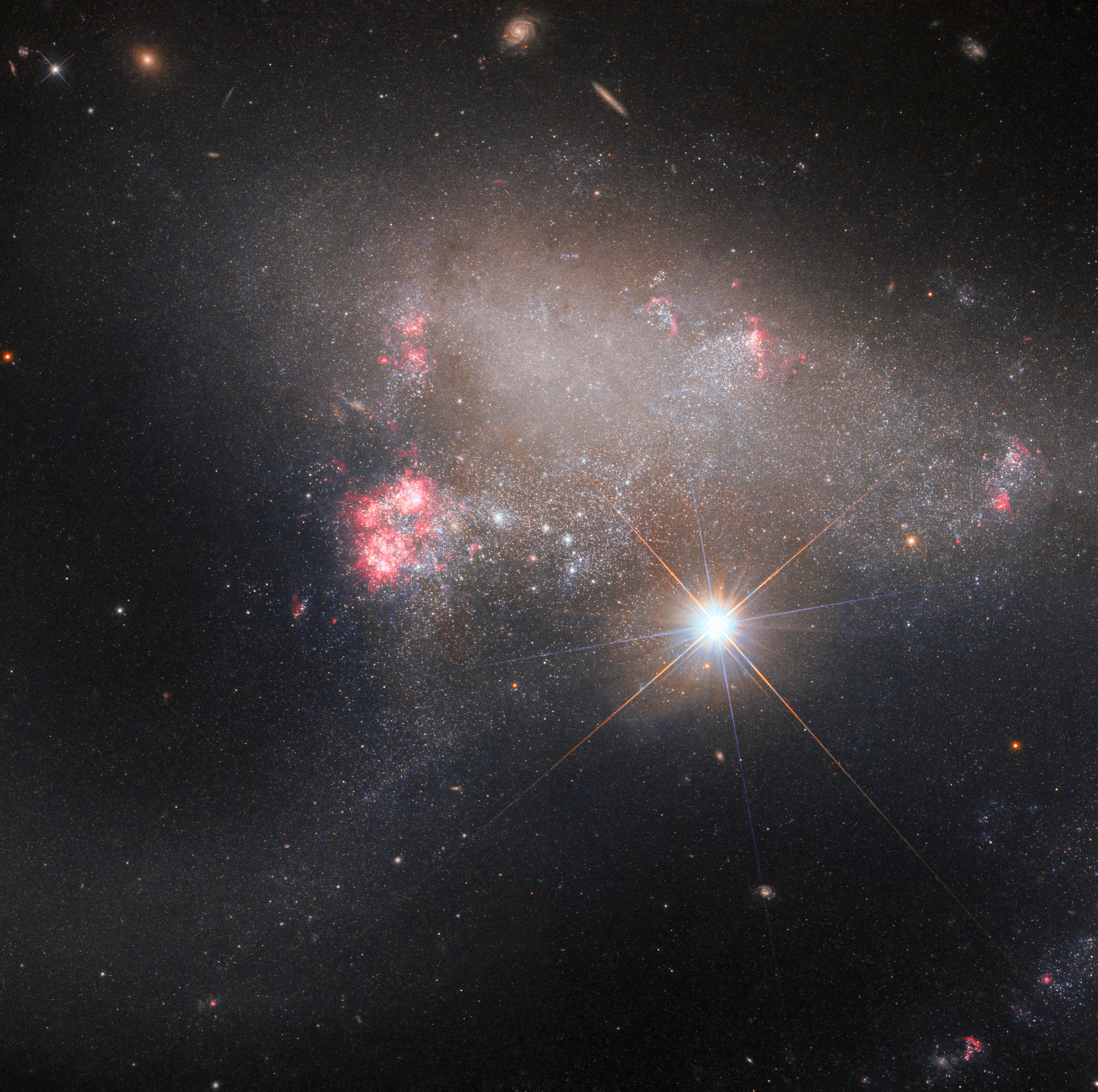 La estrella brillante BD+17 2217. Arp 263 – también conocida como NGC 3239 en primer plano y galaxia irregular Arp 263 en el fondo.