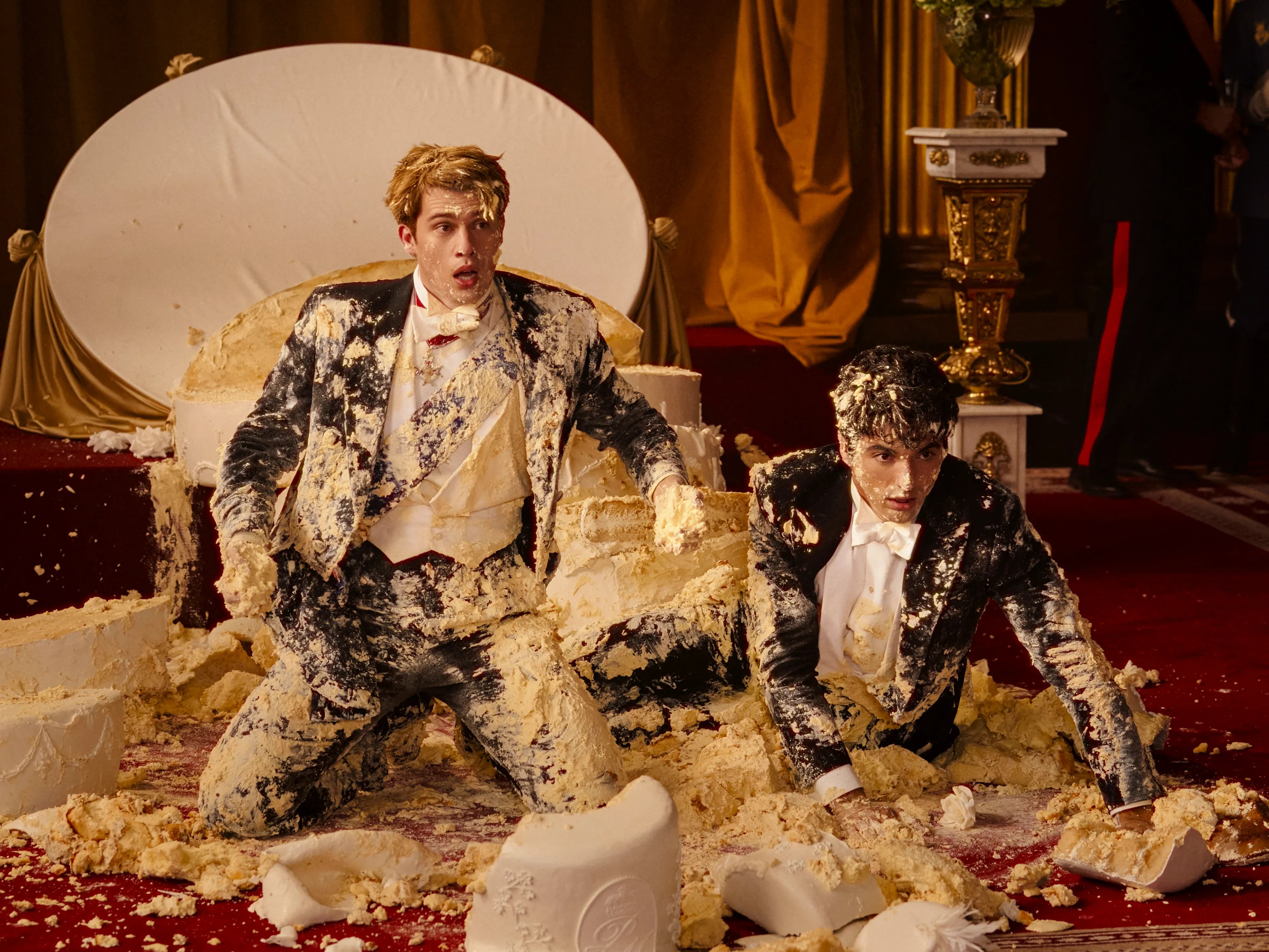 Dois homens estão cobertos de bolo em vermelho, branco e azul royal.