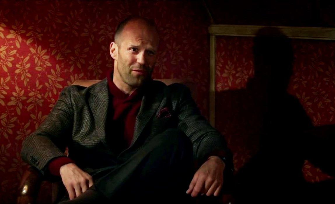 Jason Statham senta em uma cadeira em Spy (2015).