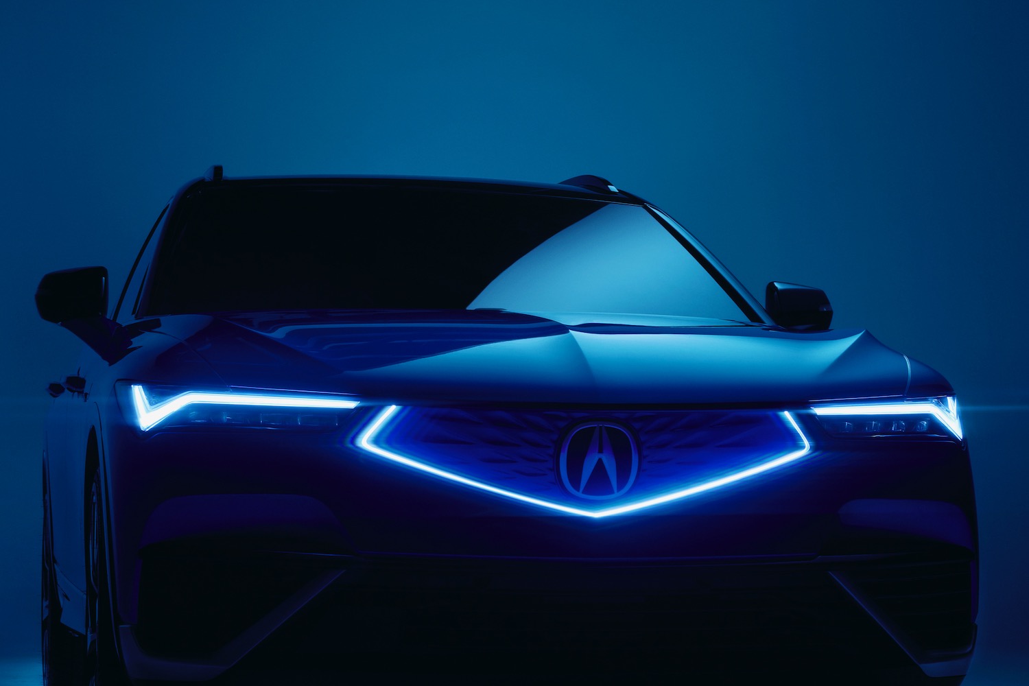 The 2024 Acura ZDX in the dark with its grille and driving lights illuminated.