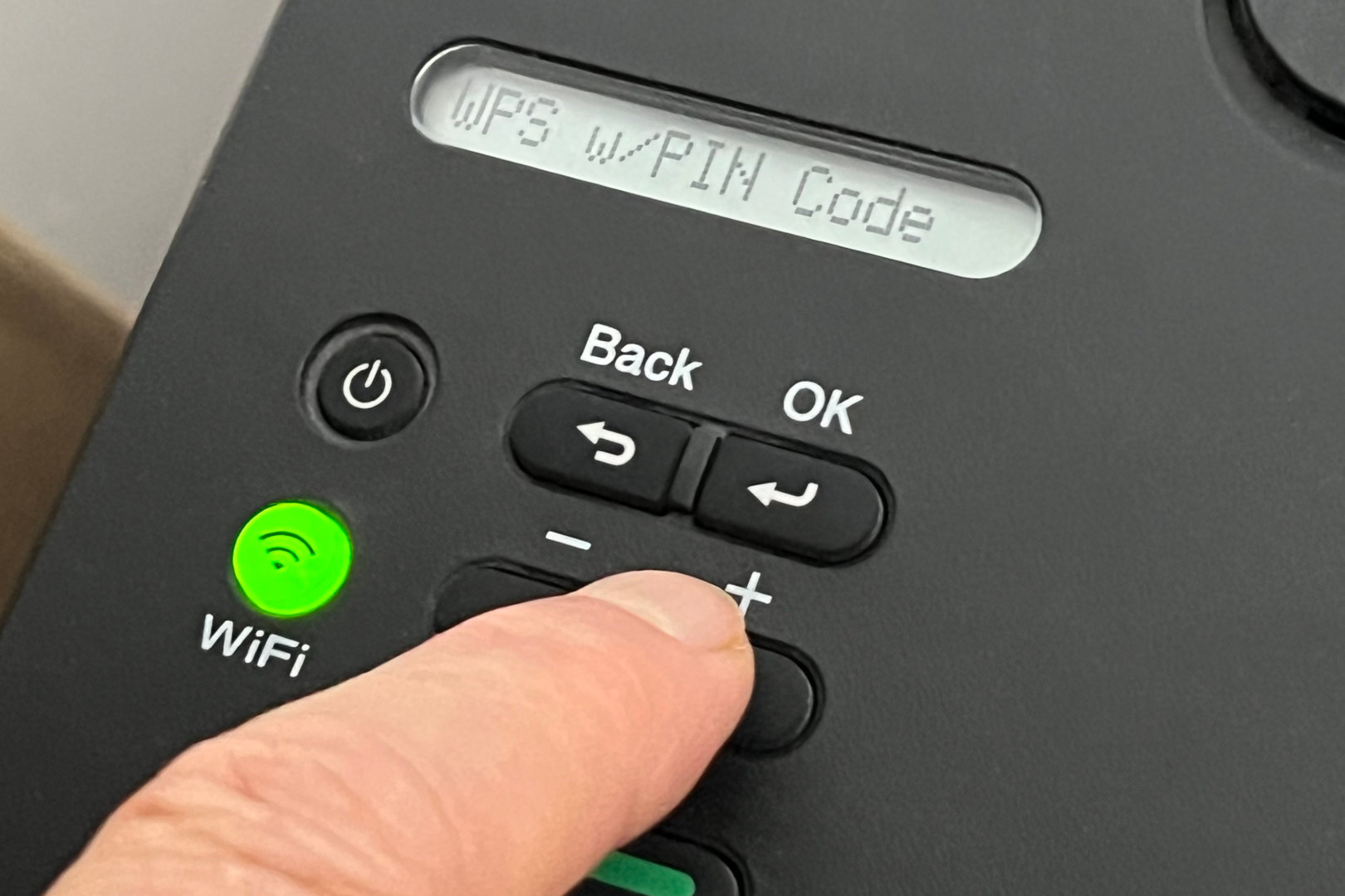 A finger navigates a printer's menus to find the WPS PIN setting.