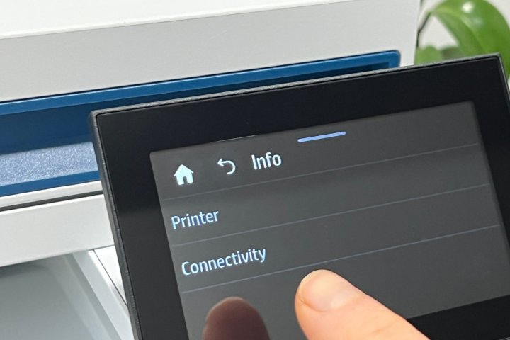 A finger points to a printer's Connectivity menu setting.