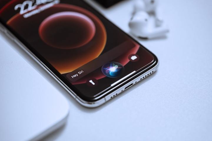 An iPhone on a table with the Siri activation animation playing on the screen.