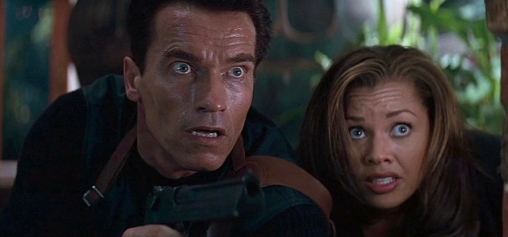 Arnold Schwarzenegger sits next to Vanessa Williams and stares in Eraser.