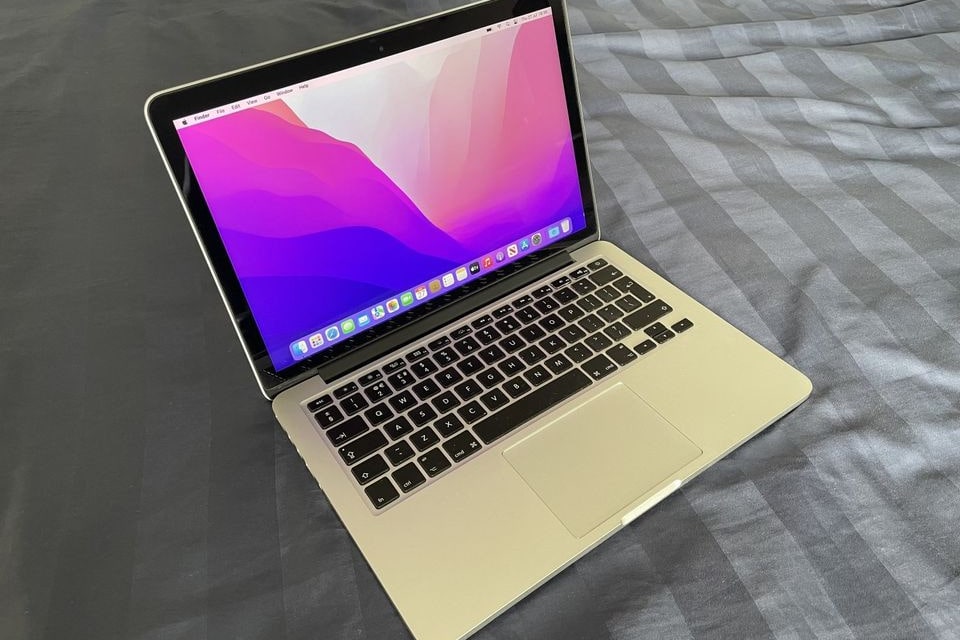 Um MacBook Pro rodando macOS Monterey em uma cama.