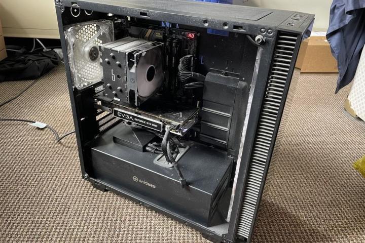 A gaming PC running with its fan spinning and side panel removed.