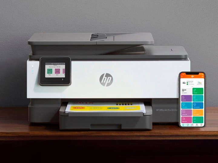 The HP - OfficeJet Pro 8034e Wireless All-In-One Inkjet Printer on a desk with a smartphone.