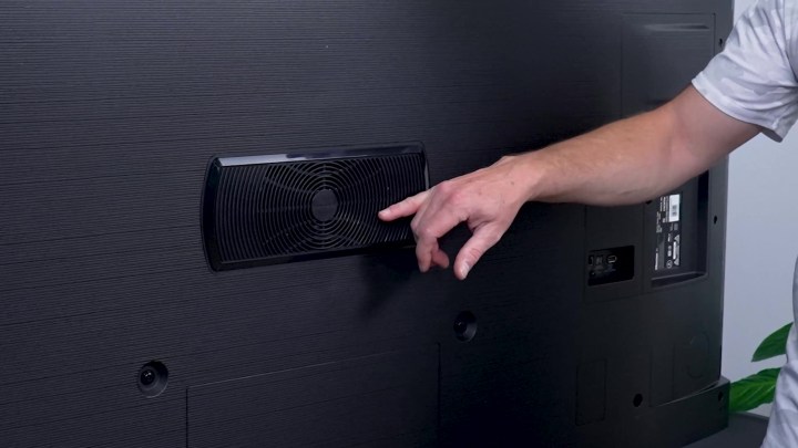 A man's arm gesturing to the speaker on the rear of a Hisense U8K. 
