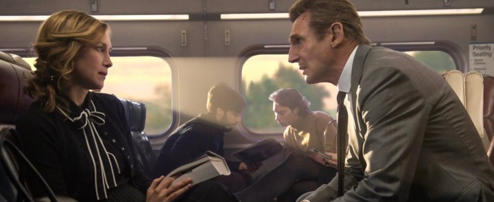Two train passengers sit across from one another in The Commuter.