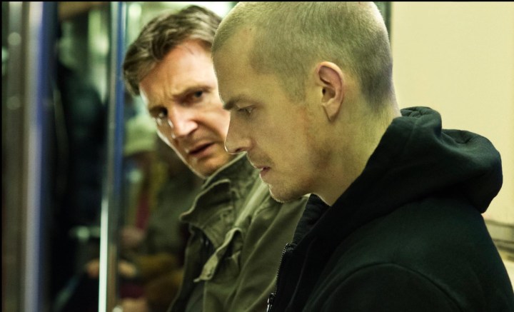 A man sits next to another man while staring down in Run All Night.