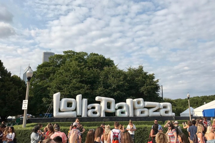 People stand in front of the Lollapalooza Chicago Welcome Sign.