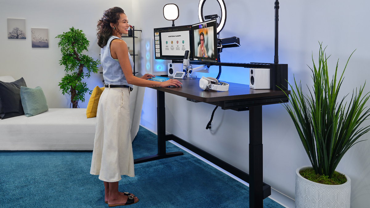 A woman stands at the Corsair Platform:6 desk as she participates in a video call.